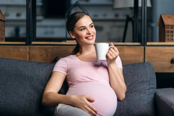 Mujer embarazada con una taza en las manos — Foto de Stock