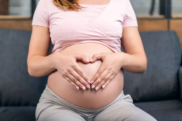妊娠中の女性の腹に心臓の形で手のひら — ストック写真