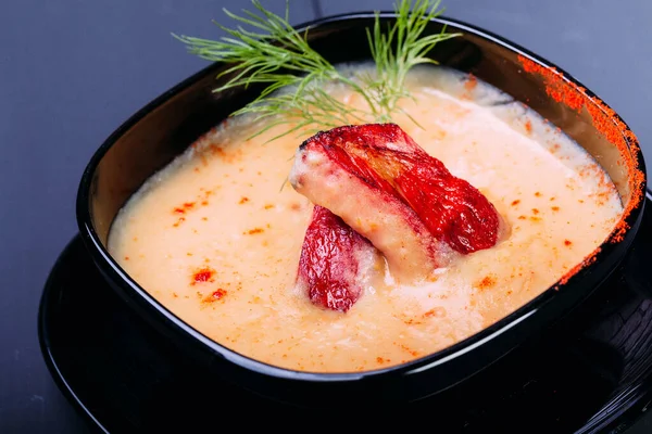 Tahta bir masada siyah tabakta balık veya somon filetosu ile krema çorbası. Çin yemeği, çorba. Ön görünüm