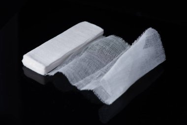 Beyaz, siyah arkaplanda beyaz pamuklu sargı bezi, yeni açılan ilk yardım gazlı bezinin tıbbi bandajı.