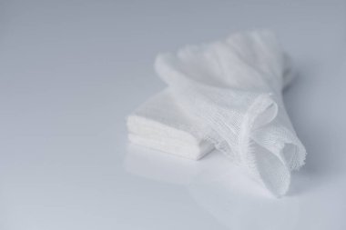 Beyaz, gri arka planda beyaz pamuklu sargı bezi, yeni açılan ilk yardım gazlı bezinin tıbbi bandajı.