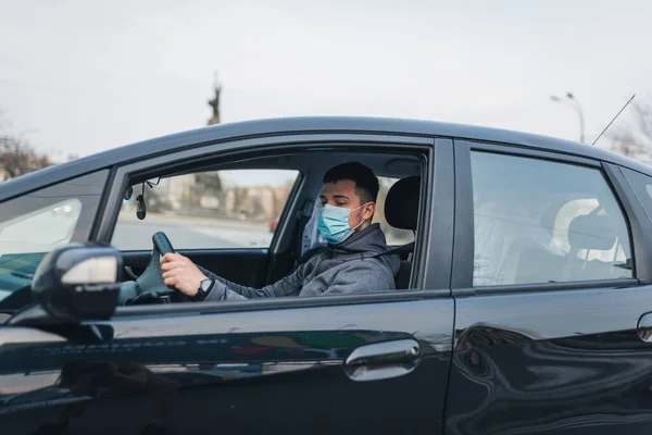a man driving a car puts on a medical mask during an epidemic, a taxi driver in a mask, protection from the virus. Driver in black car. coronavirus, disease, infection, quarantine, covid-19