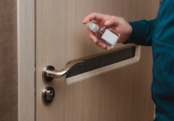 Cleaning door handles with an antiseptic during a viral epidemic. Close up view of a man hand using an antibacterial wet wipe for disinfecting a home room door joint. covid 19, coronavirus