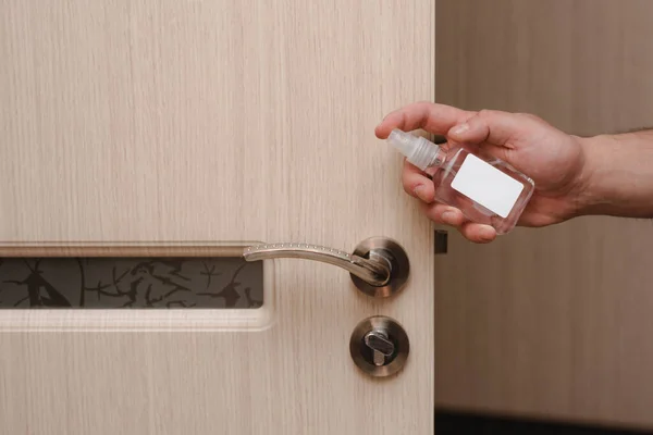 Cleaning door handles with an antiseptic during a viral epidemic. Close up view of a man hand using an antibacterial wet wipe for disinfecting a home room door joint. covid 19, coronavirus