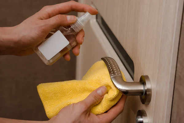 Virüs salgını sırasında temizlik kapısı antiseptikle açılıyor. Bakteriyel ıslak mendil kullanarak bir ev kapısını dezenfekte eden bir adamın yakın görüntüsü. covid 19, koronavirüs
