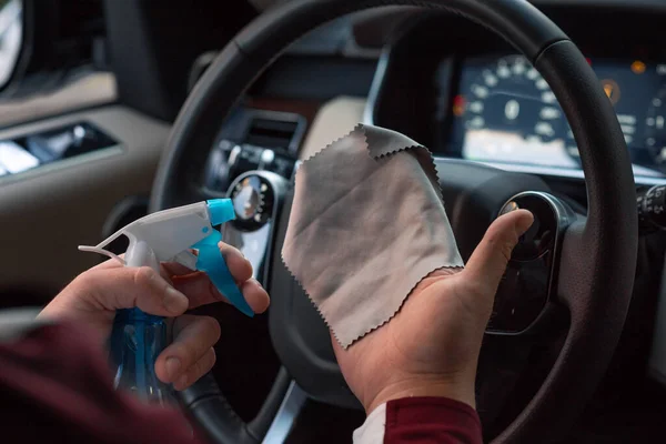 Hand with cloth cleaning car interior. A man cleaning car interior, car detailing (or valeting) concept. Selective focus. Coronavirus, covid 19