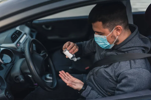 一个男人坐在车里的时候 手里拿着防腐剂凝胶 戴口罩保护病毒的男人戴面具的男人在车里Coronavirus Disease Infection Quarantine Covid 图库图片