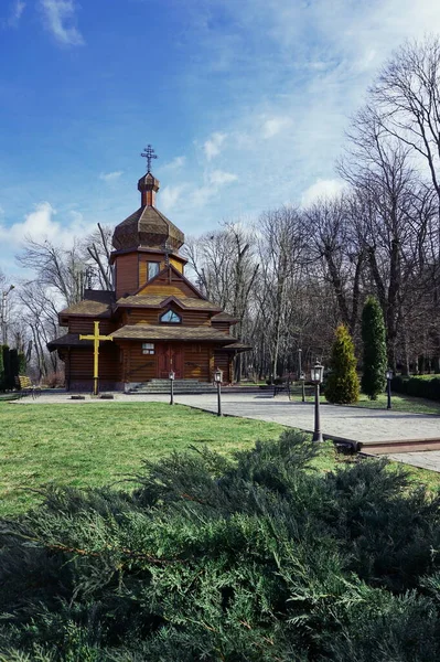 乌克兰的木制模板 去教堂的路教堂在蓝天背景的树上 明媚的春日老公园里的木制教堂 电话和平板电脑背景的木制房屋 — 图库照片