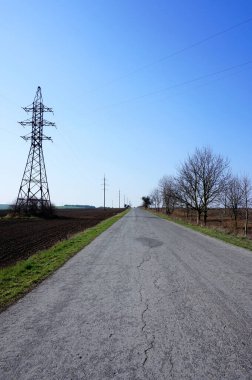 Ufkun ötesindeki yolda. Kuru bahar bölgesinin manzaraları. Yolun yakınındaki yüksek gerilim hattı. Telefon ve tablette yol ve tarla geçmişi var. Baharın başında Ukrayna topraklarında. Eski budanmış ağaçlar.