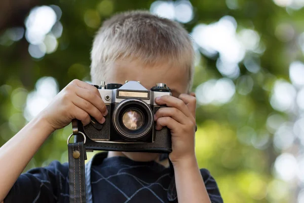 Sød lille glad dreng med vintage foto kamera udendørs - Stock-foto