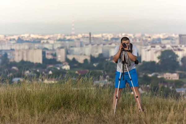 Fotógrafo com uma câmera em um tripé tirando foto com borrão — Fotografia de Stock