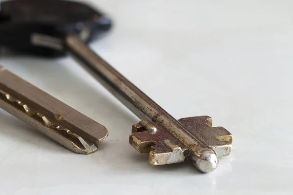 Silberner Schlüssel vor weißem Hintergrund Nahaufnahme. — Stockfoto