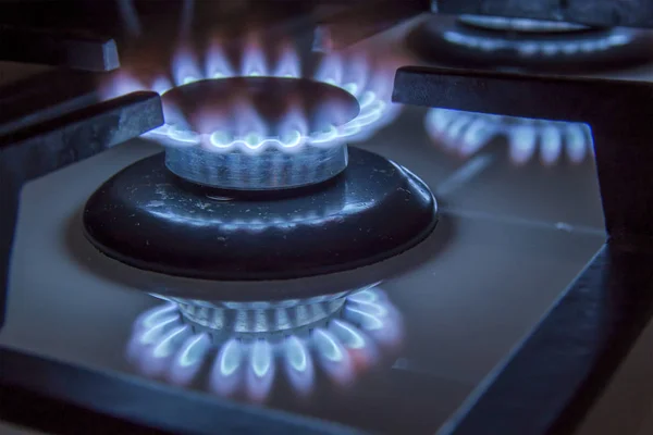 Brûlant cuisinière à gaz flammes bleues ferment dans l'obscurité sur un blac — Photo