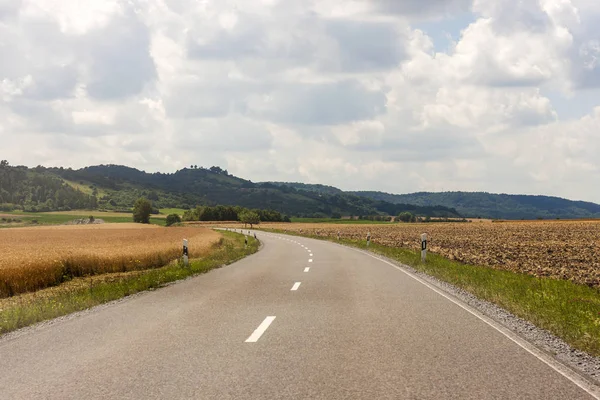 Асфальтовая сельская дорога в Германии через зеленое поле — стоковое фото