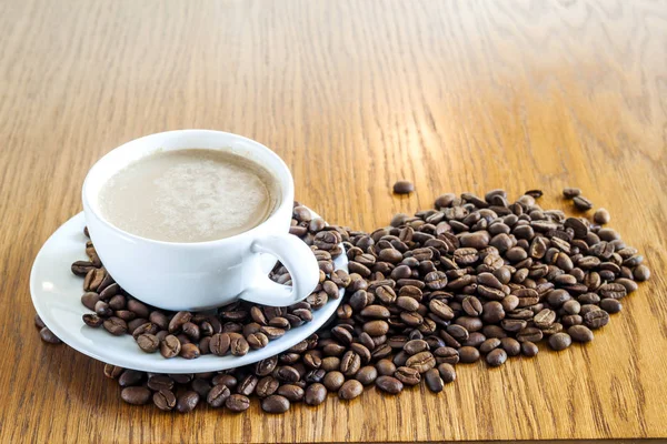 Tazza di caffè in una tazza bianca e chicchi di caffè su tavolo di legno ba — Foto Stock