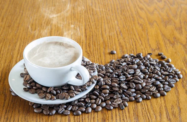 Tazza di caffè in una tazza bianca e chicchi di caffè su tavolo di legno ba — Foto Stock