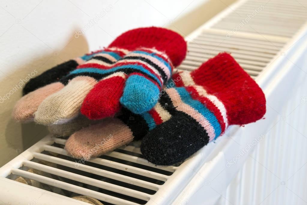 Childs knitted gloves drying on heating radiator after winter da