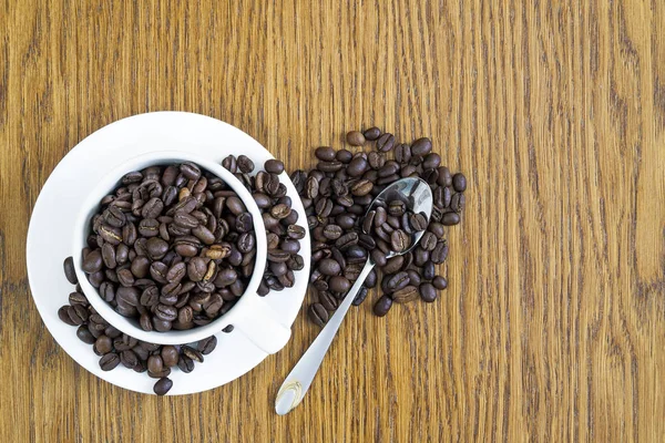 Tazza di caffè in una tazza bianca e chicchi di caffè su tavolo di legno ba — Foto Stock