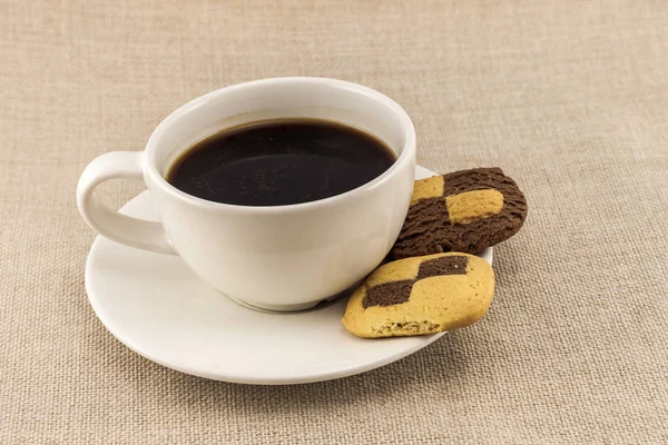 Xícara de café com xadrez biscoito como biscoitos em saco de serapilheira — Fotografia de Stock