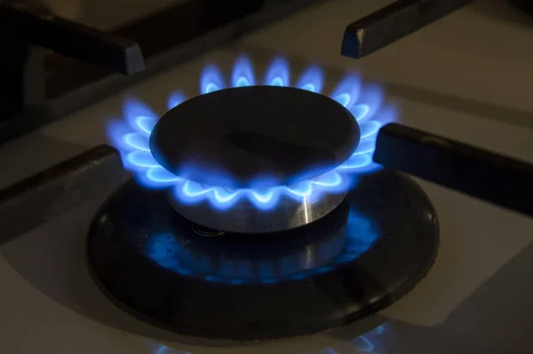 Burning gas stove hob blue flames close up in the dark on a blac — Stock Photo, Image