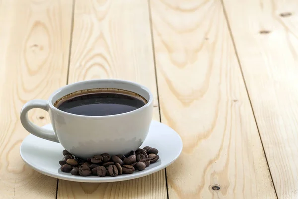 Tazza bianca con caffè fumante nero sul piatto con chicchi di caffè — Foto Stock