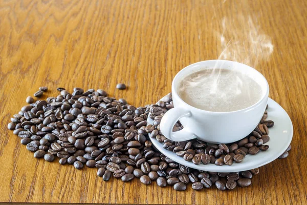 Tazza di caffè in una tazza bianca e chicchi di caffè su tavolo di legno ba — Foto Stock