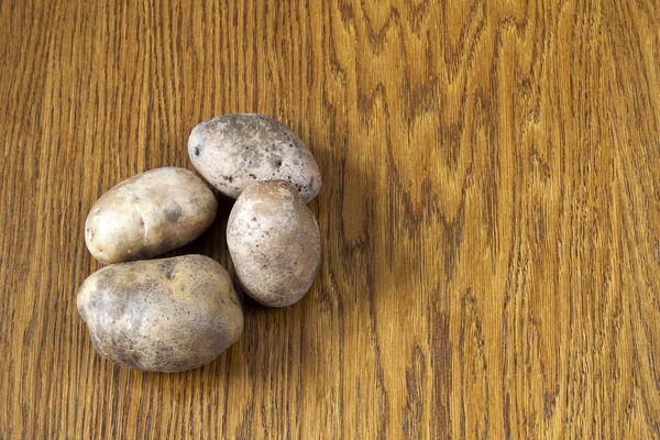 Jedzenie surowych ziemniaków. Ziemniaki na drewnianym stole. Wolnego miejsca na te — Zdjęcie stockowe