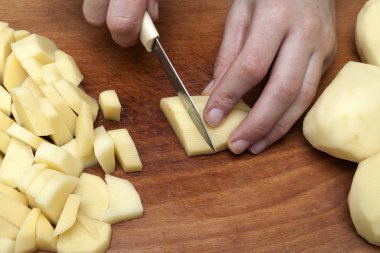 Kadın eli üzerinde ahşap boa patates Dilimleme bir bıçak kesim ile