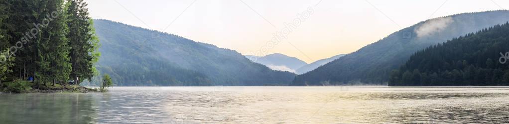 Panorama view of a big lake in morning, mountains, trees and tou