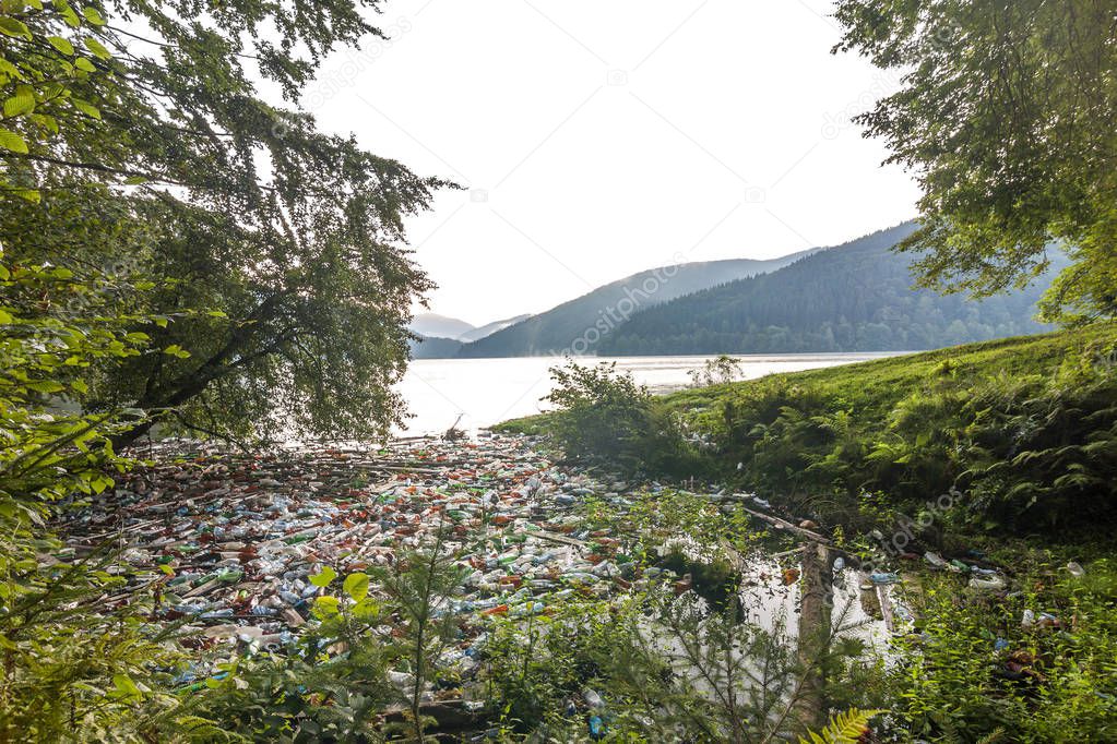 Big lake in mountains with lot of garbage trash cans and bottles