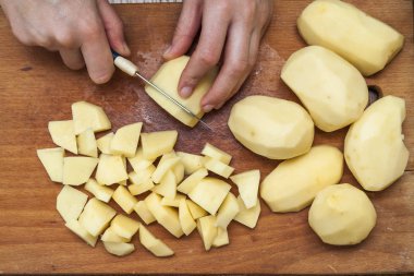 Kadın eli üzerinde ahşap boa patates Dilimleme bir bıçak kesim ile