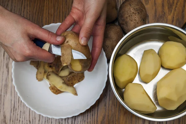 Деталь женских рук, очищающих свежий желтый картофель с кухней k — стоковое фото