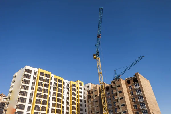 Grúa y edificio de gran altura en construcción contra el cielo azul —  Fotos de Stock