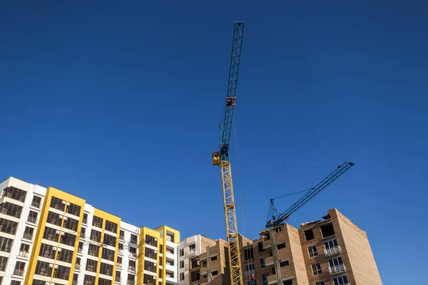 Guindaste e arranha-céus em construção contra o céu azul — Fotografia de Stock