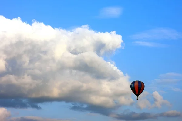 孤独な空気風船に対して白いふくらんでいる雲の前に飛んで — ストック写真