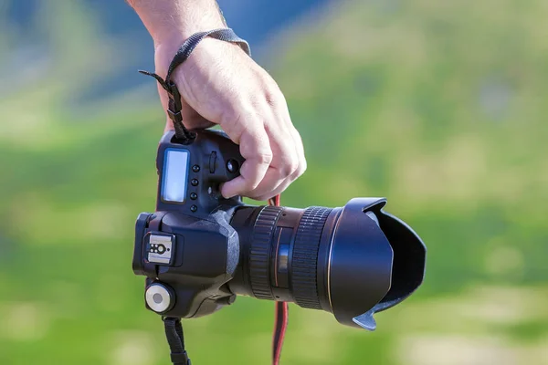 Ruka muže, který drží profesionální digitální fotoaparát na rozmazané gre — Stock fotografie