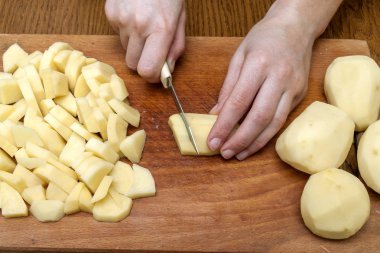 Kadın eli üzerinde ahşap boa patates Dilimleme bir bıçak kesim ile