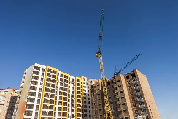 Grúa y edificio de gran altura en construcción contra el cielo azul —  Fotos de Stock