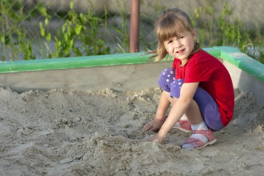 Küçük kız bir güneşli yaz günü kum havuzunda oynamayı