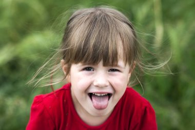 Gülümseyen küçük kız dilini gösterir. Genç sevimli küçük kız gesturi