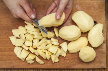 Kadın eli üzerinde ahşap boa patates Dilimleme bir bıçak kesim ile