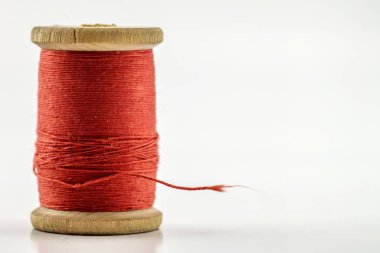 Reel or spool of red sewing thread isolated on white. Shallow de clipart