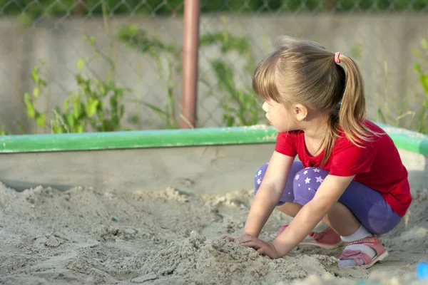 Niña jugando en sandbox en un soleado día de verano —  Fotos de Stock