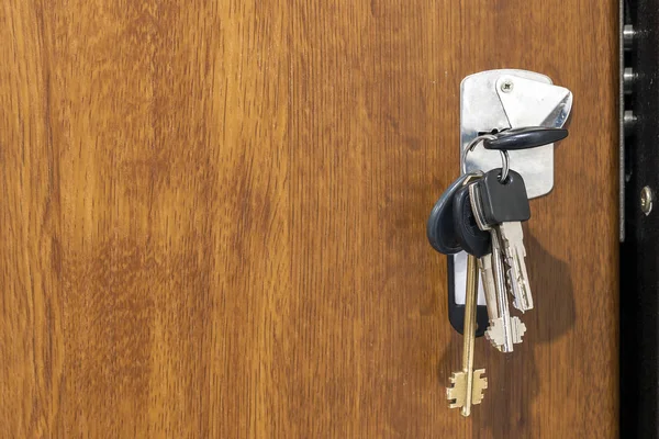 Nahaufnahme eines Bündels verschiedener Schlüssel in einem Schlüsselloch in Holztextu — Stockfoto