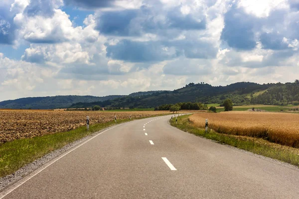 Асфальтовая сельская дорога в Германии через зеленое поле — стоковое фото