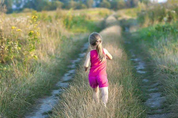 Liten flicka som springer på en fältväg — Stockfoto