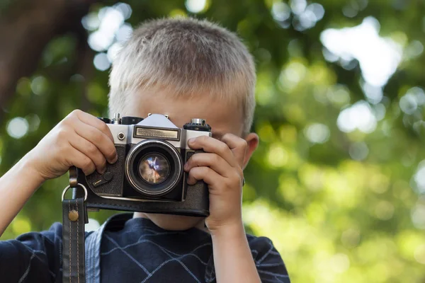 Lindo niño feliz con cámara de fotos vintage al aire libre — Foto de Stock