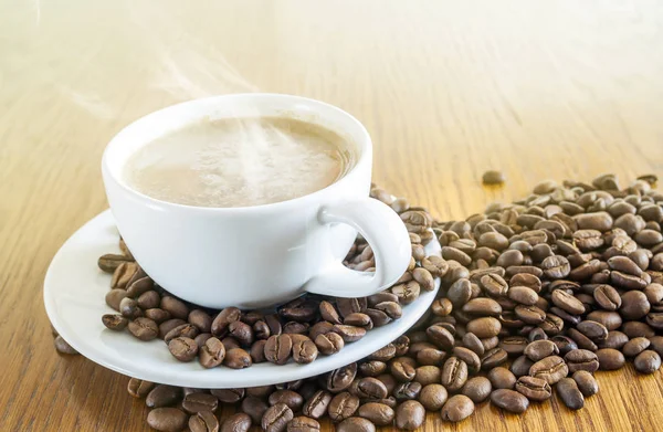 Tazza di caffè in una tazza bianca e chicchi di caffè su tavolo di legno ba — Foto Stock