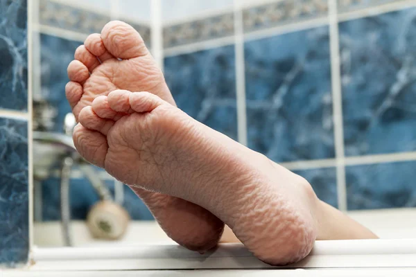 Морщинистые босые ноги выходят из ванны. Молодой человек гетти — стоковое фото