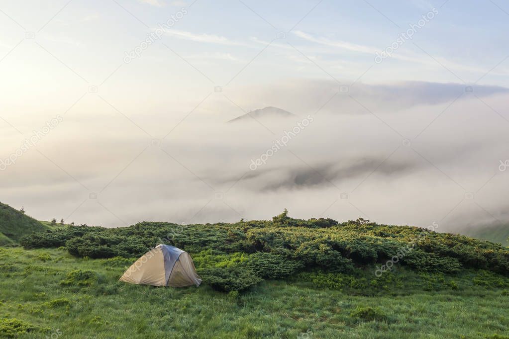 Panorama of cold foggy summer morning and tourist hikers tent in